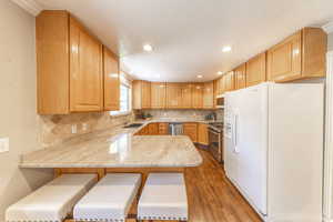 Kitchen featuring appliances with stainless steel finishes, light wood-type flooring, a sink, a peninsula, and recessed lighting