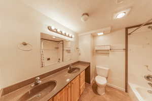 Bathroom featuring toilet, a textured ceiling, a sink, and tile patterned flooring