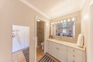 Bathroom with crown molding, a stall shower, vanity, toilet, and ensuite bathroom