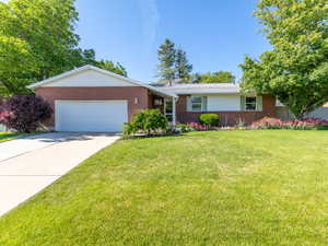 Single story home featuring brick siding, an attached garage, and driveway