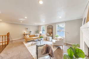 Carpeted living area with recessed lighting, baseboards, ornamental molding, and a fireplace