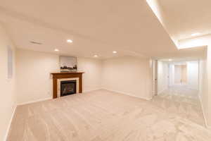 Finished below grade area featuring light carpet, recessed lighting, a fireplace, and baseboards