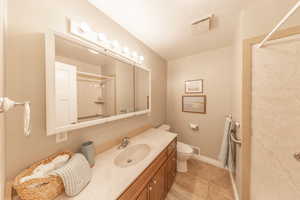 Bathroom with visible vents, walk in shower, toilet, and vanity