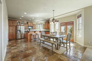 Dining space with recessed lighting, baseboards, a notable chandelier, and stone tile flooring