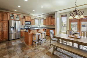 Kitchen featuring dark countertops, appliances with stainless steel finishes, a breakfast bar area, a chandelier, and recessed lighting