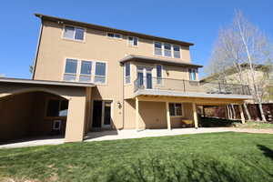 Rear view of house with a patio, stucco siding, and a yard