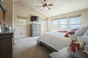 Bedroom featuring light colored carpet, a ceiling fan, baseboards, and lofted ceiling