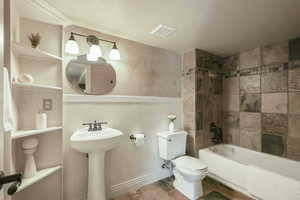 Full bathroom with toilet, visible vents, shower / washtub combination, and a wainscoted wall