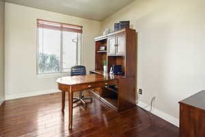 Office area featuring baseboards and dark wood-style flooring