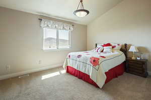 Bedroom featuring visible vents, baseboards, vaulted ceiling, and carpet