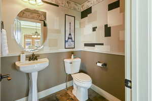 Bathroom featuring baseboards, a notable chandelier, and toilet