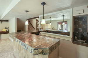 Bar with a sink, carpet floors, and decorative light fixtures