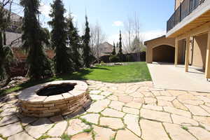 View of yard featuring a patio, fence, a balcony, and an outdoor fire pit