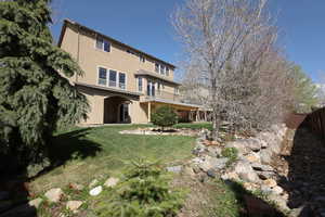 Back of property featuring a lawn, fence, stucco siding, and a balcony