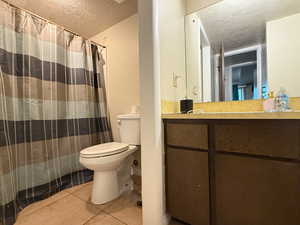 Full bath with vanity, toilet, a textured ceiling, tile patterned floors, and a shower with curtain