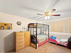Bedroom with a ceiling fan and light carpet