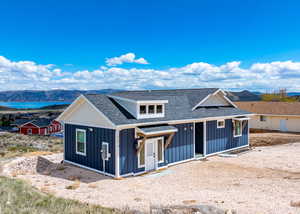 Modern farmhouse style home with board and batten siding, a shingled roof, and a mountain view