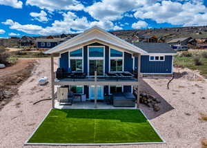 Back of property with a deck, a hot tub, an outdoor structure, a yard, and a patio