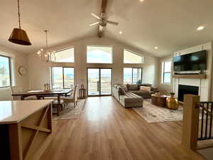 Living area featuring light wood-style floors, vaulted ceiling with beams, a fireplace, and a wealth of natural light