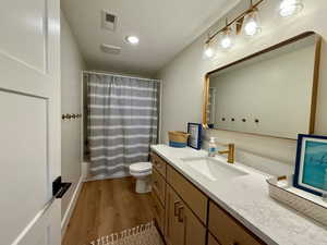 Full bath featuring vanity, toilet, wood finished floors, shower / tub combo
