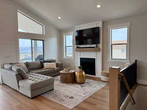 Living area with a fireplace, vaulted ceiling, recessed lighting, and light wood-style flooring