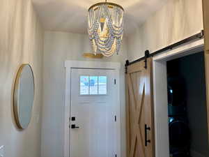 Foyer with a barn door, and a notable chandelier