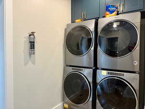 Laundry area featuring baseboards, stacked washer and clothes dryer, and cabinet space