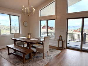 Dining area with a notable chandelier, light wood-style flooring, baseboards, a towering ceiling, and a mountain view