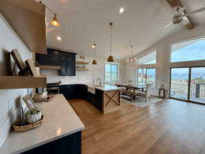 Kitchen featuring open shelves, a peninsula, high vaulted ceiling, light countertops, and a sink