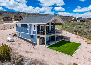 Back of house featuring roof with shingles, a wooden deck, board and batten siding, a patio area, and a yard