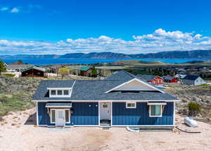 View of front of property featuring a water and mountain view, a shingled roof, and board and batten siding