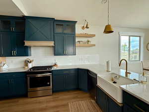 Kitchen featuring backsplash, decorative light fixtures, a sink, stainless steel appliances, and light wood-style flooring