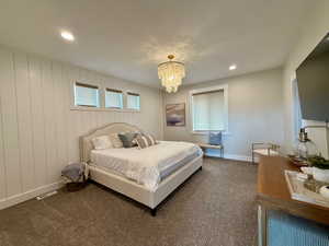 Bedroom featuring an inviting chandelier, baseboards, dark colored carpet