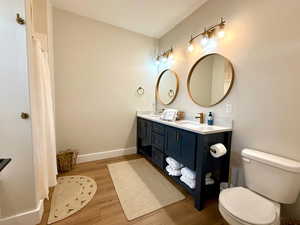 Full bath featuring double vanity, a sink, wood finished floors, and toilet