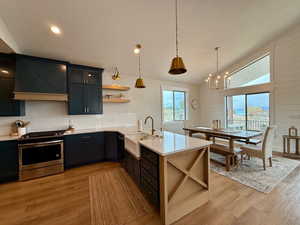 Kitchen with open shelves, a notable chandelier, a sink, light countertops, and gas range