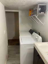 Laundry area with baseboards, washer and dryer, a textured ceiling, and cabinet space