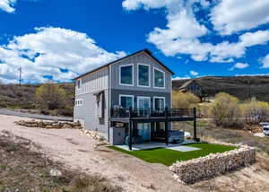 Back of property featuring a hot tub, board and batten siding, a patio area, and a deck