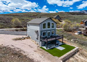 Rear view of house featuring a patio, a shingled roof, board and batten siding, and a deck with mountain view