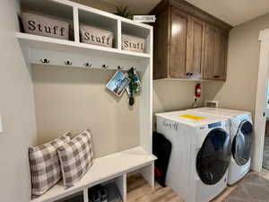 Clothes washing area featuring light wood-type flooring, cabinet space, and independent washer and dryer