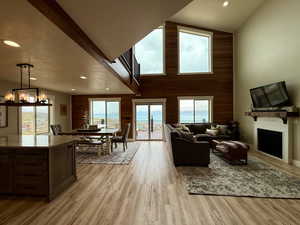 Living room with a fireplace, wood walls, a notable chandelier, recessed lighting, and light wood-style flooring