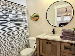 Full bath with vanity, a shower with shower curtain, toilet, and an inviting chandelier
