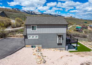 View of home's exterior with a shingled roof, board and batten siding, and a deck with mountain view