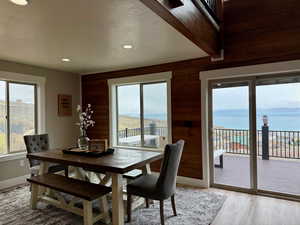 Dining space with wooden walls, light wood-style floors, recessed lighting, and a textured ceiling