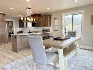 Dining space with washer / dryer, baseboards, light wood-style floors, recessed lighting, and a notable chandelier