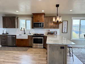 Kitchen featuring a breakfast bar area, appliances with stainless steel finishes, a sink, a peninsula, and light wood-style floors