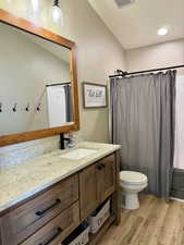 Bathroom with vanity, toilet, a shower with shower curtain, wood finished floors, and visible vents