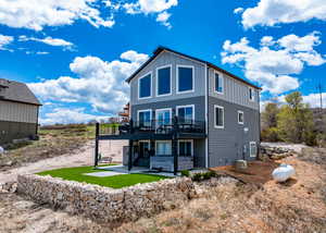 Rear view of property with a wooden deck, a patio, board and batten siding, and a jacuzzi