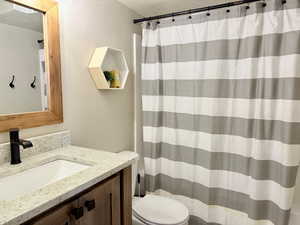 Full bath featuring toilet, a textured ceiling, curtained shower, and vanity