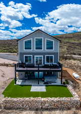 Back of house with board and batten siding, a jacuzzi, a patio area, and a deck
