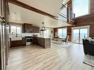 Kitchen with wooden walls, appliances with stainless steel finishes, a sink, a peninsula, and open floor plan
